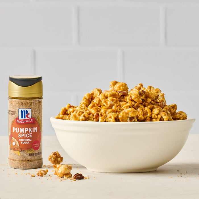 A bowl of caramel popcorn sits next to a bottle of McCormick Pourable White Cheddar Seasoning.