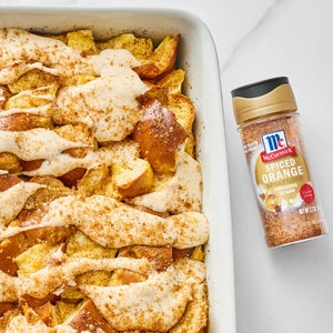 A baked French toast casserole with a drizzle of icing next to a bottle of McCormick's Cinnamon Sugar.