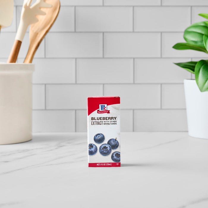 A box of Mccormick Blueberry Extract 1 Fl Oz With Other Natural Flavors stands on a white marble countertop in a kitchen setting.