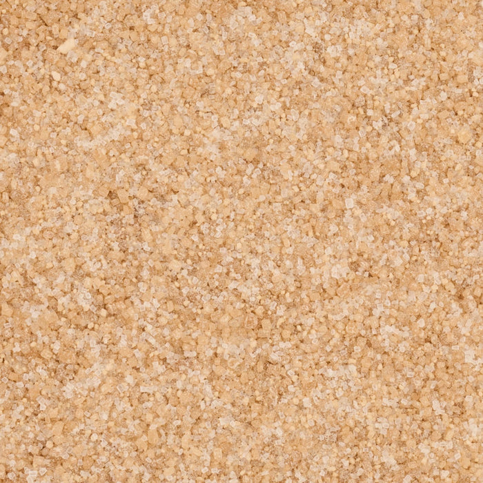A close-up, top-down view reveals the crystalline texture of Mccormick Salted Caramel Finishing Sugar Edible Cake Decoration 3.81 Oz, showing a mix of light brown and clear sugar crystals.