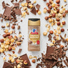 A bottle of McCormick Chocolate Hazelnut Flavored Seasoning is surrounded by chocolate pieces and hazelnuts.