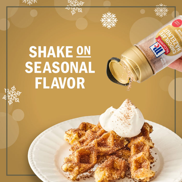 A hand sprinkles McCormick Pumpkin Pie Spice onto waffles topped with whipped cream, highlighting a seasonal flavor.
