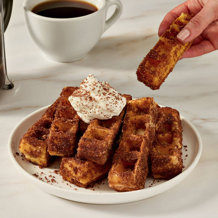 A cup of hot chocolate with whipped cream and McCormick Hazelnut topping sits next to a bottle of the topping.