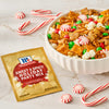 A bowl of McCormick Sweet &amp; Snick Holiday Party Mix is surrounded by candy canes and peppermint candies, showcasing a festive holiday snack.