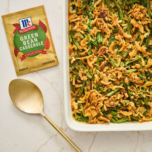 McCormick Green Bean Casserole seasoning packet is displayed next to a golden spoon and a freshly baked green bean casserole.