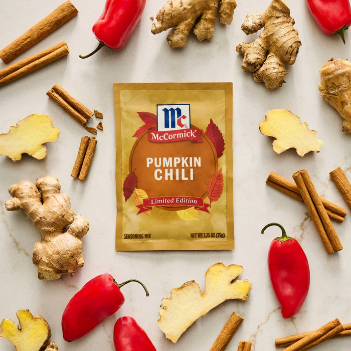McCormick Pumpkin Chili seasoning packet surrounded by cinnamon sticks, ginger, and red peppers.