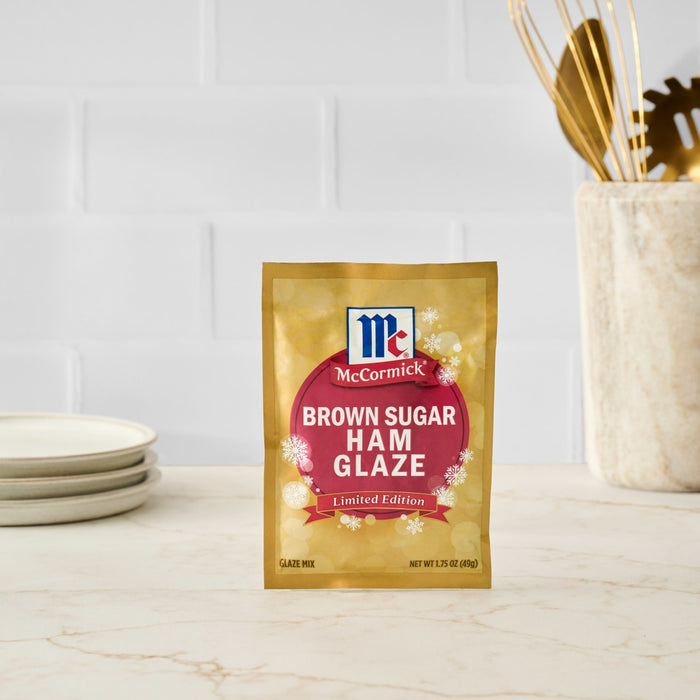 A packet of McCormick Brown Sugar Ham Glaze sits on a countertop, ready to enhance a holiday ham.
