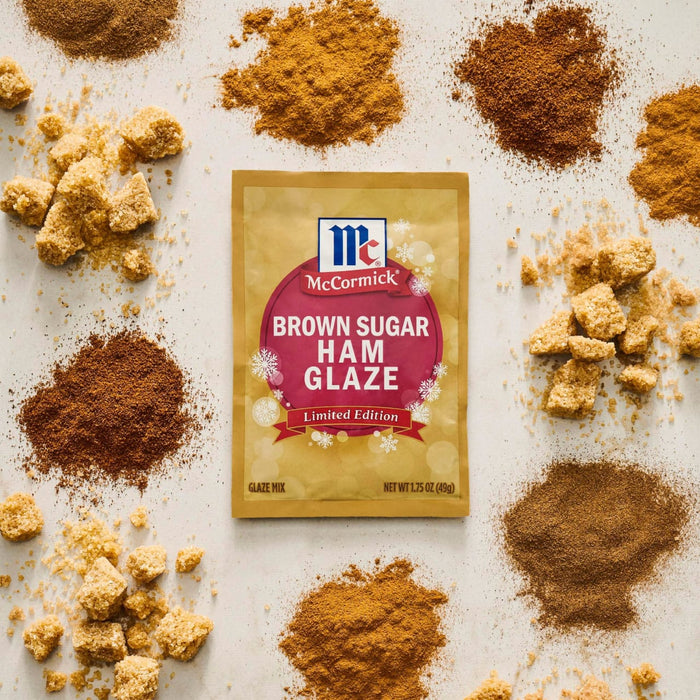 A packet of McCormick Brown Sugar Ham Glaze is surrounded by piles of brown sugar in various forms.