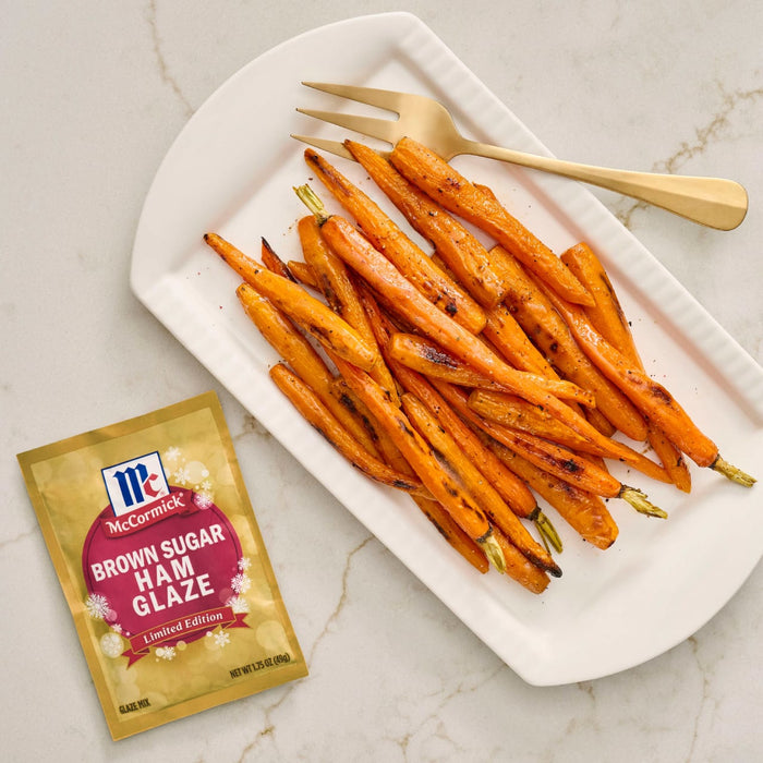 A plate of glazed carrots next to a packet of McCormick Brown Sugar Ham Glaze.