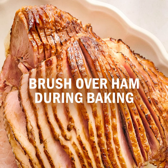 A glazed ham is shown sliced and ready to be brushed during baking.