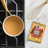 A packet of McCormick Brown Gravy mix is displayed next to a saucepan filled with gravy and a whisk.