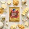 A packet of McCormick Brown Butter Gravy mix is surrounded by butter, garlic, and onions.