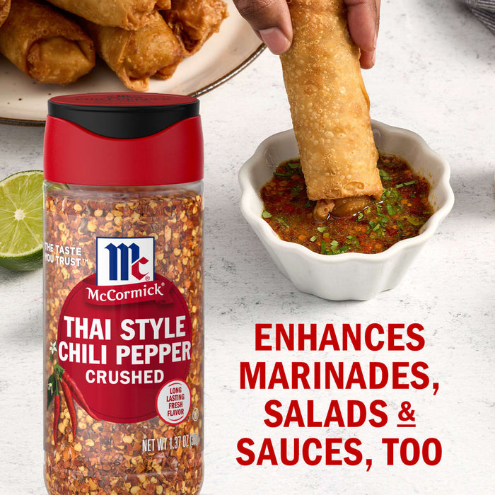 A jar of McCormick Thai Style Chili Pepper Crushed is featured next to a bowl of dipping sauce and egg rolls highlighting its versatility in enhancing marinades salads and sauces.