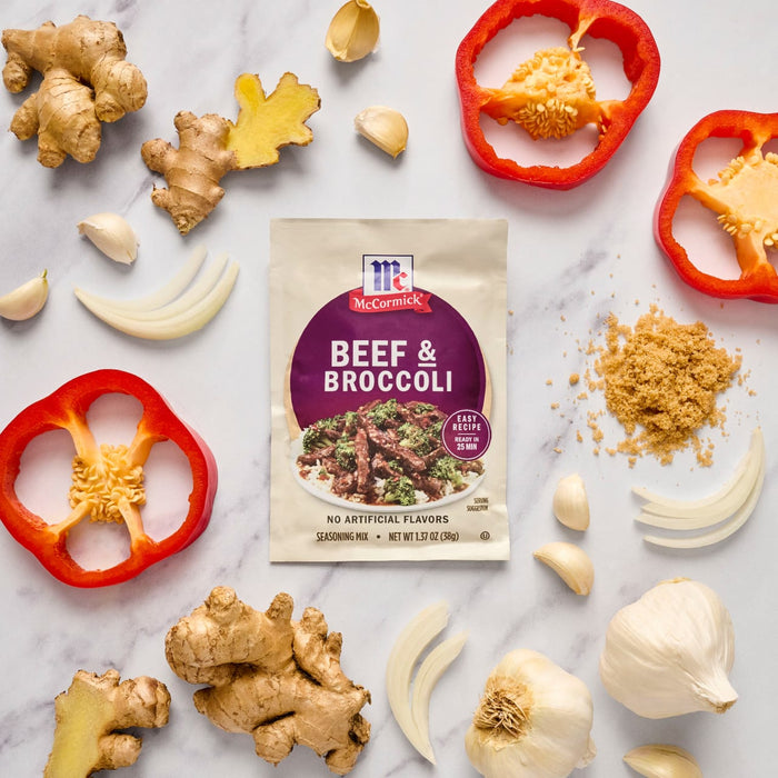 A McCormick Beef &amp; Broccoli seasoning mix packet is surrounded by fresh ingredients like ginger garlic red bell pepper onion and brown sugar.