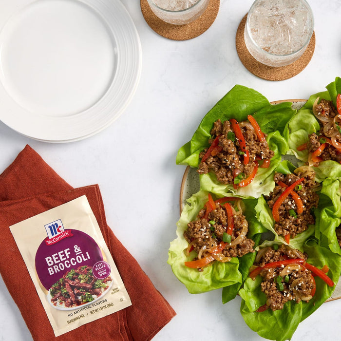 A packet of McCormick Beef &amp; Broccoli seasoning mix is displayed next to lettuce wraps filled with beef and vegetables.