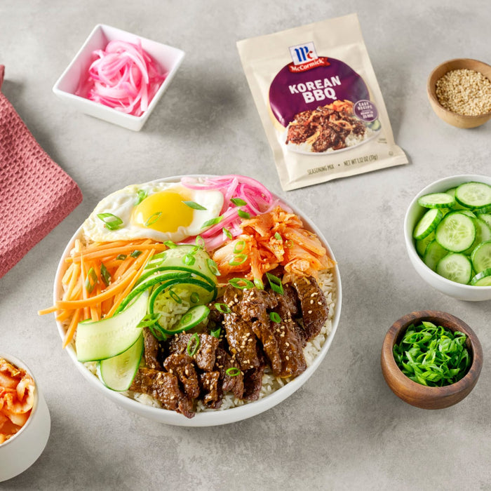 A Korean BBQ bowl with rice vegetables meat and a fried egg along with a McCormick Korean BBQ seasoning packet.