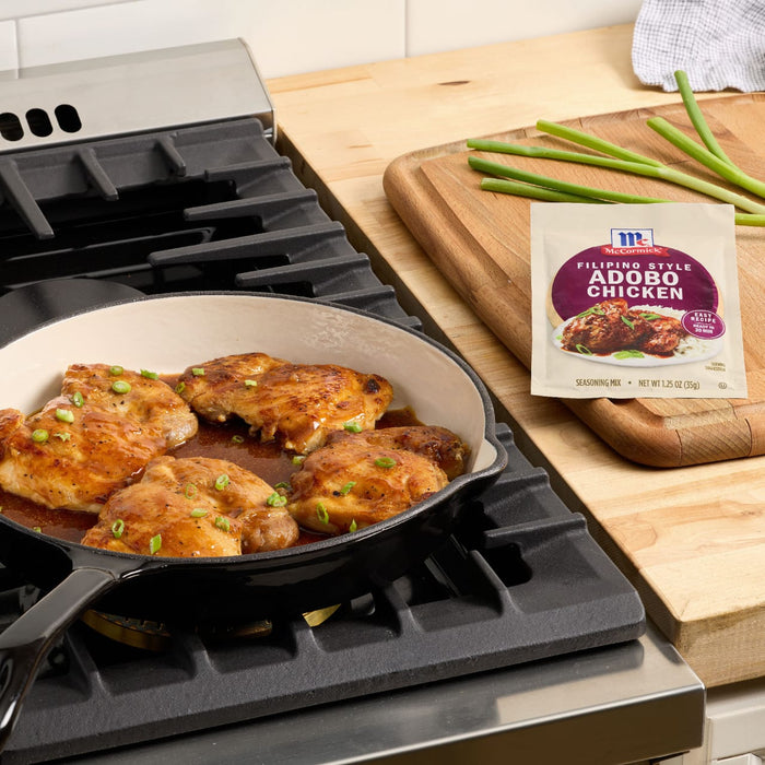 McCormick Filipino Style Adobo Chicken seasoning mix is displayed next to a pan of cooked chicken on a stovetop.