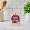 A packet of McCormick Filipino Style Adobo Chicken seasoning mix sits on a kitchen counter.