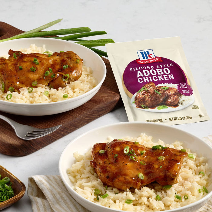Two bowls of Filipino style adobo chicken and rice are displayed next to a McCormick seasoning mix packet.
