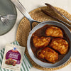 A package of McCormick Filipino Style Adobo Chicken seasoning mix is displayed next to a pan of cooked chicken in adobo sauce.