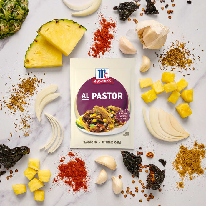 A packet of McCormick Al Pastor seasoning mix is surrounded by ingredients like pineapple onion garlic and spices.