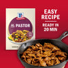 A package of McCormick Al Pastor seasoning mix is displayed next to a skillet of cooked Al Pastor meat highlighting the easy recipe thats ready in 20 minutes.