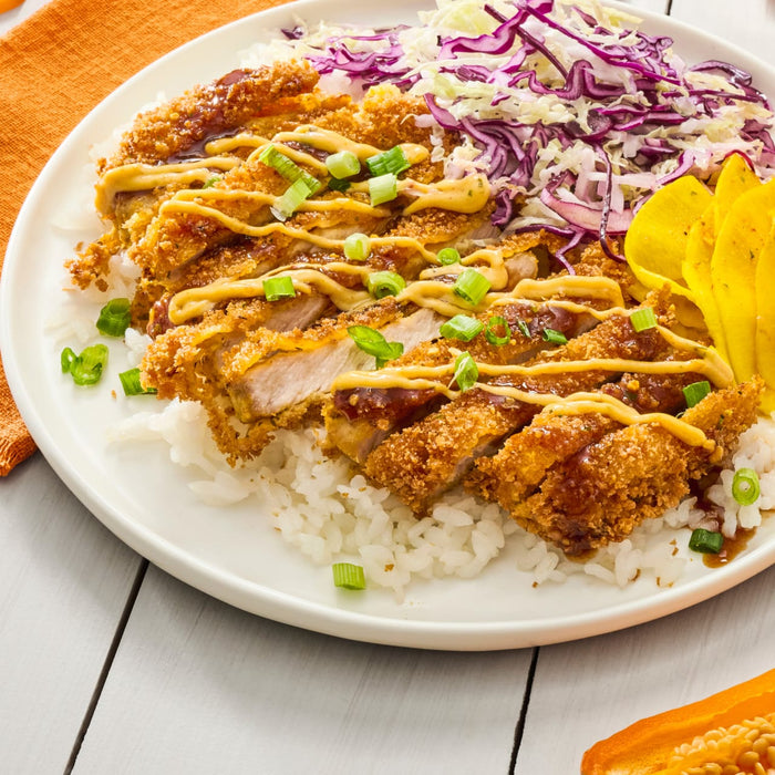 A plate of Japanese food with breaded chicken rice cabbage and pickled ginger.