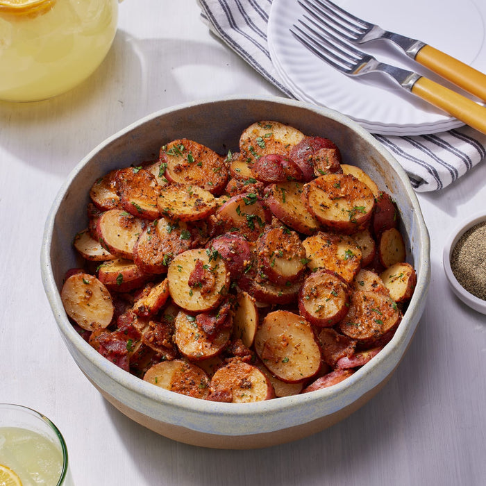 A bowl of red potatoes with herbs and spices.