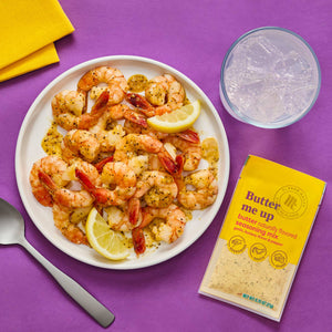 A plate of Lemon Herb Shrimp Scampi from Good &amp; Gather is displayed with lemon wedges a glass of water a spoon and a packet of the seasoning mix.