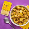 A bowl of roasted potatoes seasoned with Native Snax Butter Me Up seasoning blend is displayed next to the seasoning packet and a spoon.