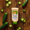 A bottle of McCormick Jalapeño Mayonnaise Dressing is displayed on a wooden surface surrounded by fresh whole and sliced jalapeños.
