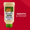 A squeeze bottle of McCormick Jalapeno Mayonnaise Dressing stands on its green cap against a red background next to the words Smooth and Creamy.