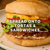 A close up of a torta filled with meat, beans, lettuce, tomato, and a yellow sauce with overlaid text reading SPREAD ONTO TORTAS AND SANDWICHES.