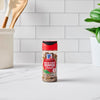 A bottle of McCormick Hatch Chile Pepper Crushed is centered on a white marble countertop with a white subway tile backsplash.