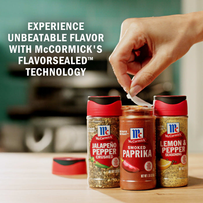 A hand peels the seal off a McCormick Smoked Paprika spice jar which sits next to McCormick JalapeA?o Pepper and Lemon &amp; Pepper seasoning jars.