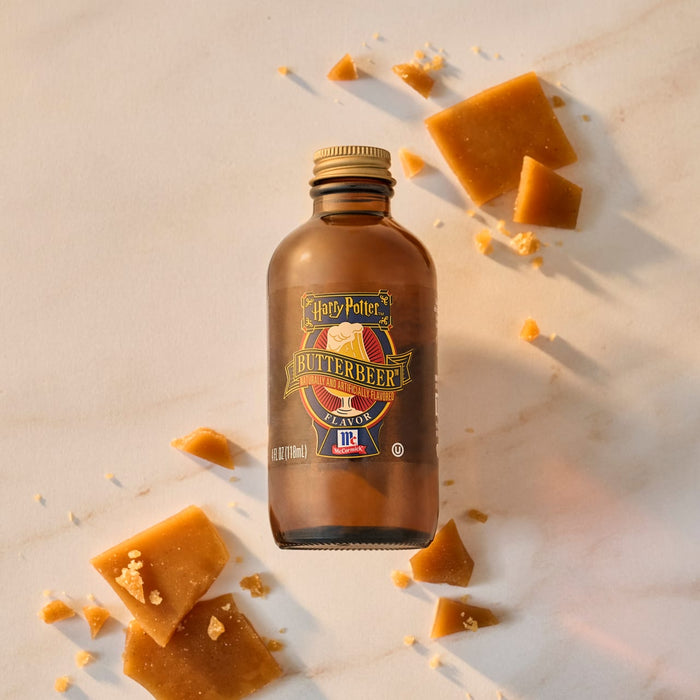 A bottle of Harry Potter Butterbeer Flavor by McCormick is surrounded by pieces of butterscotch candy.