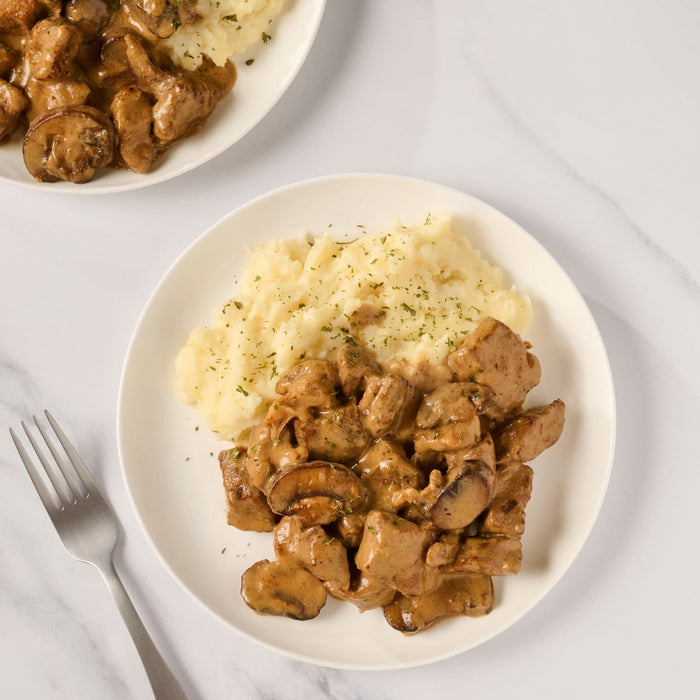 A plate of creamy mushroom and pork stew served with mashed potatoes.