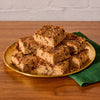 A golden plate holds a pile of freshly baked chocolate chip cake squares, finished with a delightful sprinkle of Mccormick Harry Potter Chocolate Frog Finishing Sugar, 3.47 Oz.