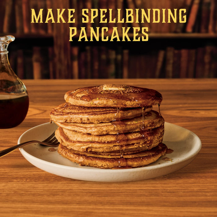 A tall stack of pancakes on a plate is topped with butter, syrup, and a sprinkle of Mccormick Harry Potter Chocolate Frog Finishing Sugar, 3.47 Oz, with the text Make Spellbinding Pancakes above.