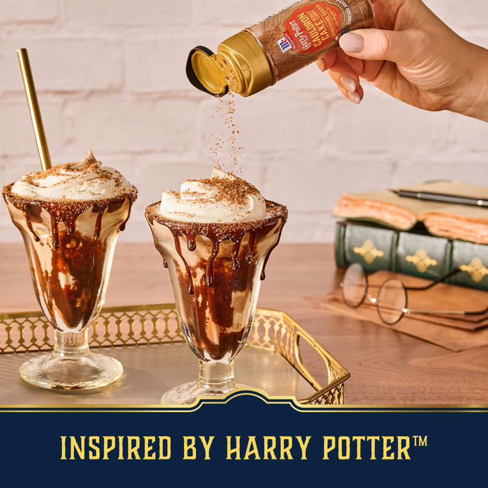A hand sprinkles Mccormick Harry Potter Cauldron Cake Finishing Sugar, 3.43 Oz over two chocolate sundaes to create a magical, Harry Potter-inspired dessert.