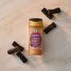 A bottle of Mccormick Harry Potter Licorice Wand Finishing Sugar, 3.39 Oz is on a marble surface with pieces of black licorice.