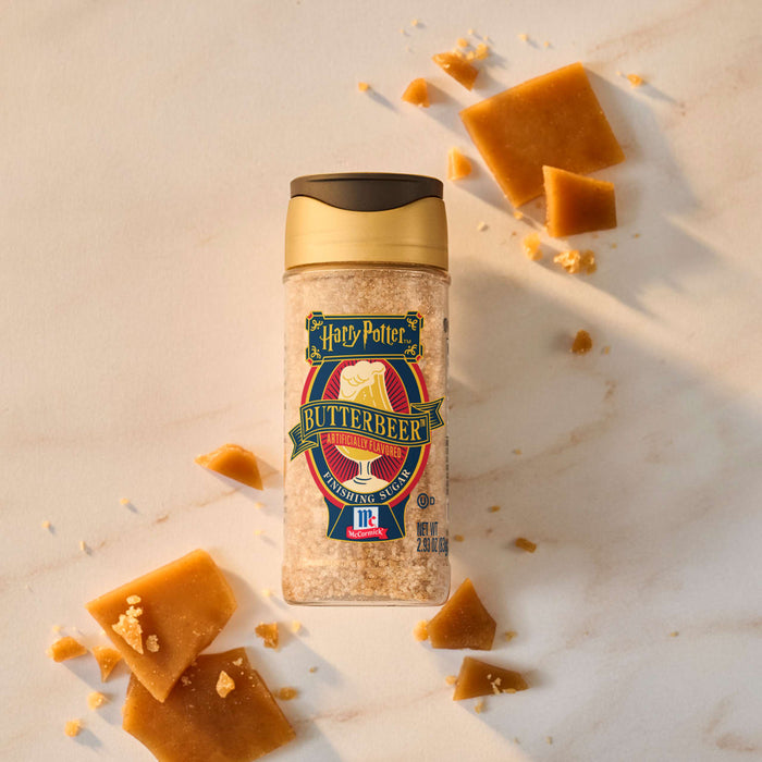 A bottle of McCormick Harry Potter Butterbeer Finishing Sugar is surrounded by pieces of butterscotch candy.