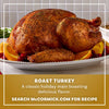 A golden brown roast turkey seasoned with Mccormick Turkey Rub, 1.25 Oz is presented on a white platter garnished with orange slices and cranberries.