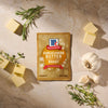 A package of Mccormick Garlic And Herb Butter Roast Seasoning Mix, 1.0 Oz is displayed on a stone surface surrounded by fresh garlic cloves, sprigs of rosemary and thyme, and pats of butter.