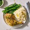 A roasted chicken leg seasoned with Mccormick Garlic And Herb Butter Roast Seasoning Mix, 1.0 Oz is served on a plate with mashed potatoes and green beans.