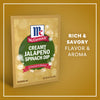A package of Mccormick Creamy Jalapeno Spinach Dip Seasoning Mix, 0.87 Oz is displayed against a golden background with festive snowflakes and text highlighting its rich and savory flavor and aroma.