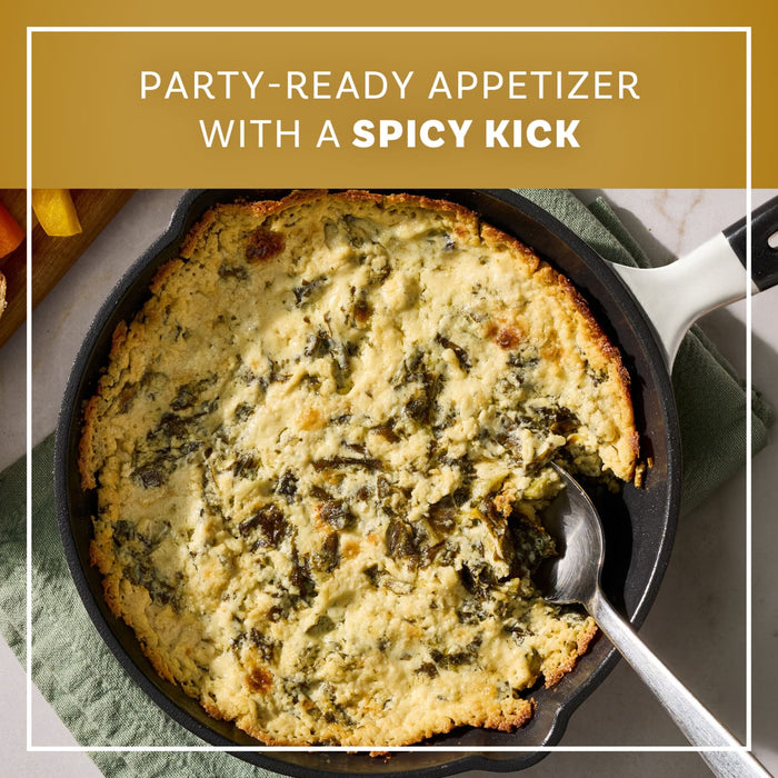 A golden brown skillet of baked appetizer made with Mccormick Creamy Jalapeno Spinach Dip Seasoning Mix 0.87 Oz is served with a spoon and fresh vegetables.