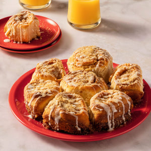 A pan of glazed sweet rolls topped with a sprinkle of Mccormick English Toffee Finishing Sgr 3.7 Oz, with the product bottle and other kitchen items in the background.