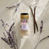 A jar of McCormick Gourmet Organic Garlic is displayed with vanilla beans and lavender sprigs on a lace background.