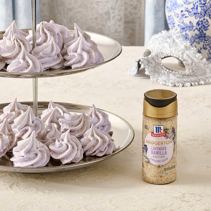 A two-tiered tray displays purple meringue cookies next to a bottle of McCormick Mardi Gras blend.